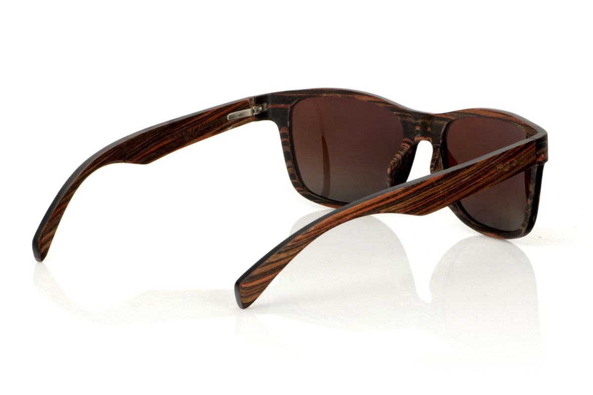 Gafas de Madera Natural de Ébano ELEGANCE. Las gafas de sol de madera ELEGANCE destacan por su montura menos angulosa, diseñadas para adaptarse a caras más anchas o para quienes prefieren las gafas sobredimensionadas. Este modelo se caracteriza por su construcción única, con madera de ébano laminada en el exterior e interior y láminas de madera de arce intercaladas a contraveta, y por el detalle de la curvatura de la montura en la cogida a las patillas ofreciendo no solo un efecto visual impresionante sino también una estructura robusta. Con unas medidas generosas de 155x50mm y un calibre de 55, estas gafas son la elección perfecta para quienes buscan combinar comodidad con un estilo audaz y elegante. Venta al Por Mayor y Detalle | Root Sunglasses® 